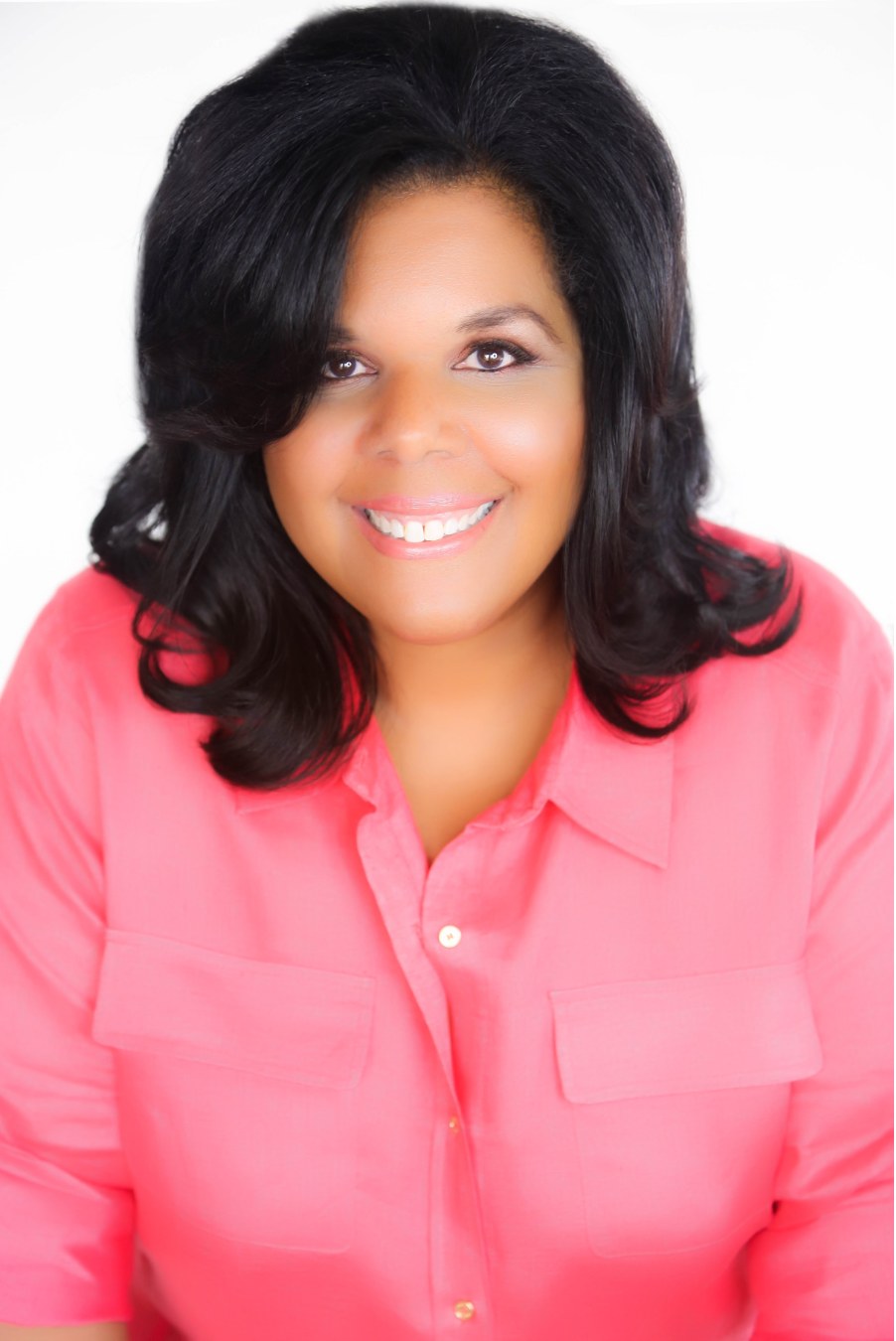 Mari — Mariana Cooper — smiling warmly in a coral blouse