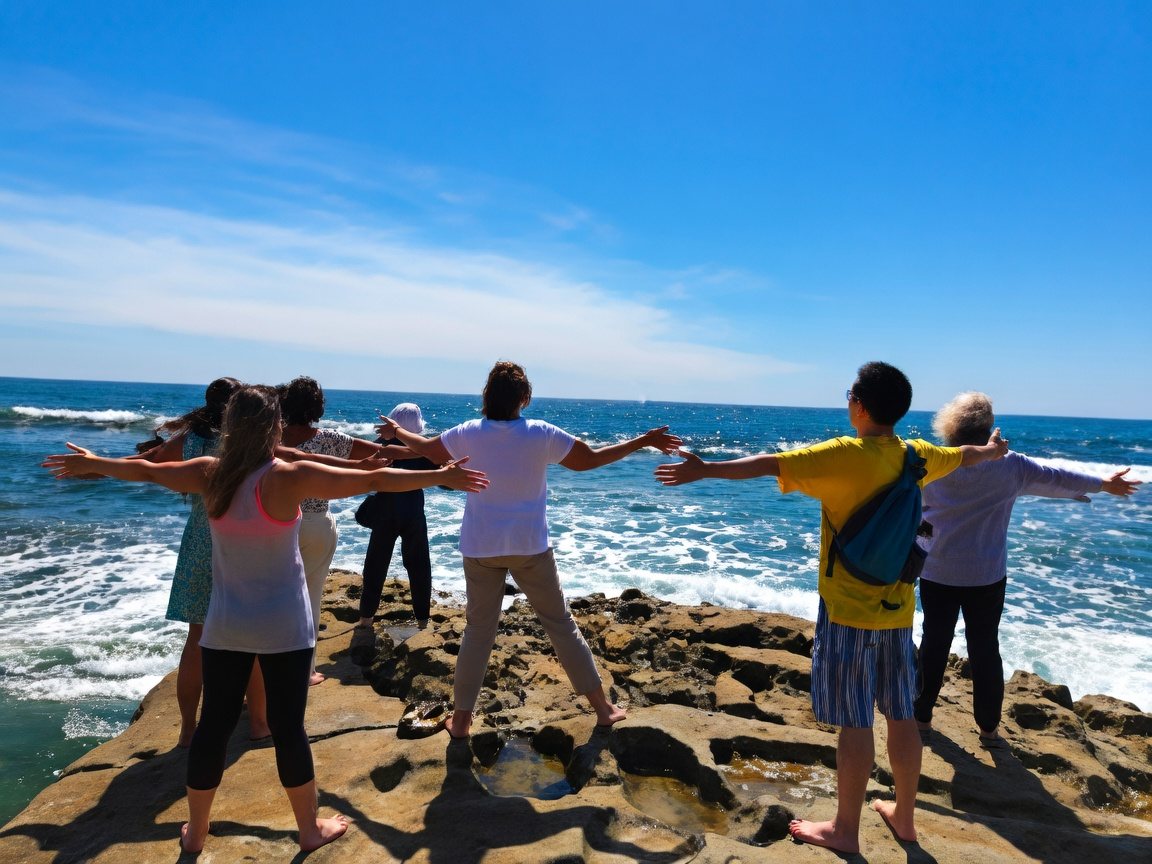Retreat group on the rocks at the La Jolla shoreline with arms outstretched to the ocean
